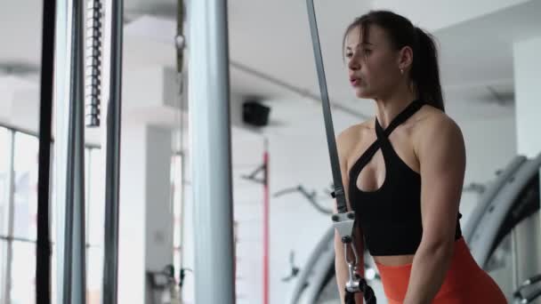 Athletic woman trains back muscles in lat simulator in gym. Girl training in the gym.  - Video, Çekim