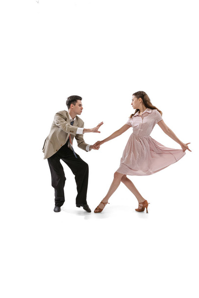 Young man and woman in vintage retro style outfits dancing social dance isolated on white background. Timeless traditions, 1960s american fashion style and art - Photo, Image