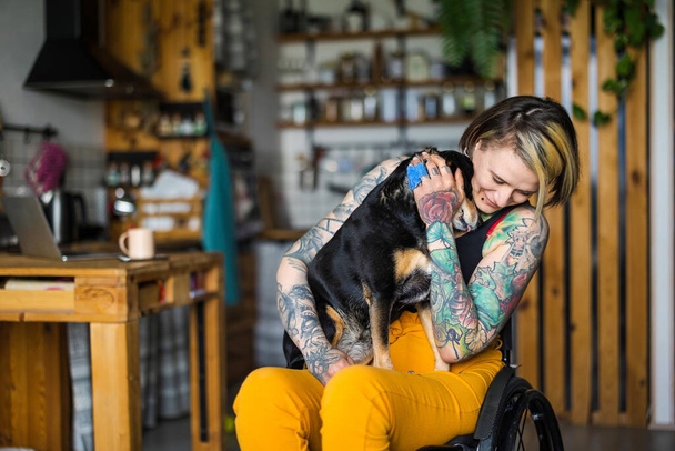 Νεαρή γυναίκα με αναπηρία με το σκύλο της στο σπίτι - Φωτογραφία, εικόνα