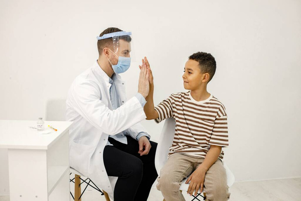 Male doctor give a high five to a boy after a vaccination - Φωτογραφία, εικόνα