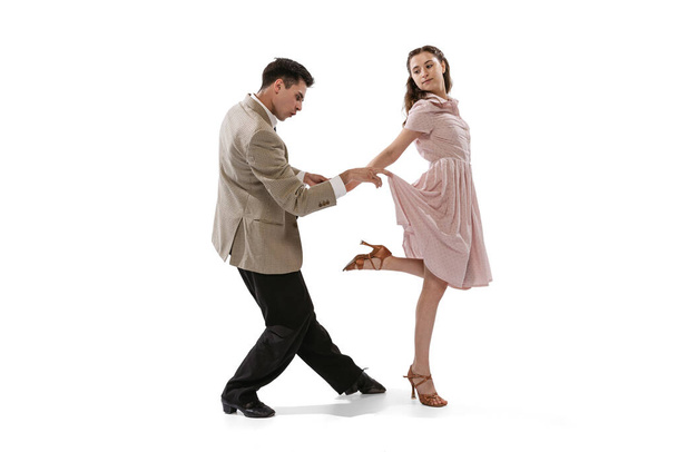 Young man and woman in vintage retro style outfits dancing social dance isolated on white background. Timeless traditions, 1960s american fashion style and art - Foto, Bild