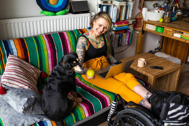 Young woman with disability with her dog at home - 写真・画像