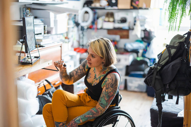 Portrait of an young tattooed woman in a wheelchair at home - Foto, Bild