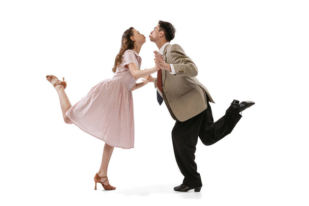 Young man and woman in vintage retro style outfits dancing social dance isolated on white background. Timeless traditions, 1960s american fashion style and art - 写真・画像