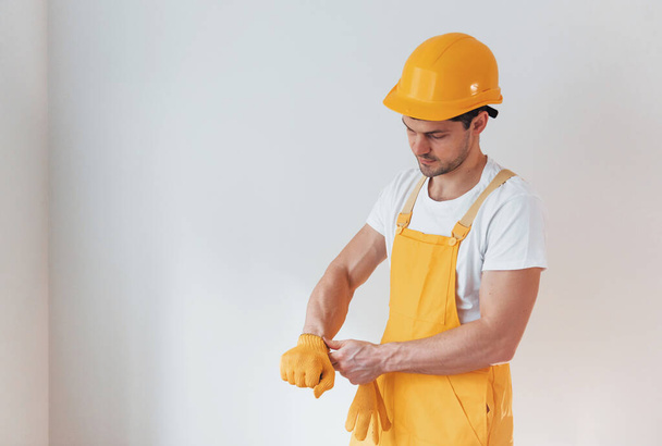 Handyman in yellow uniform preparing for work indoors. House renovation conception. - Photo, image