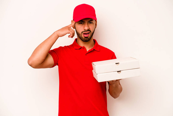 Fiatal spanyol futár kezében pizza elszigetelt fehér háttér mutató csalódást gesztus mutatva mutatva mutatva mutatóujj. - Fotó, kép