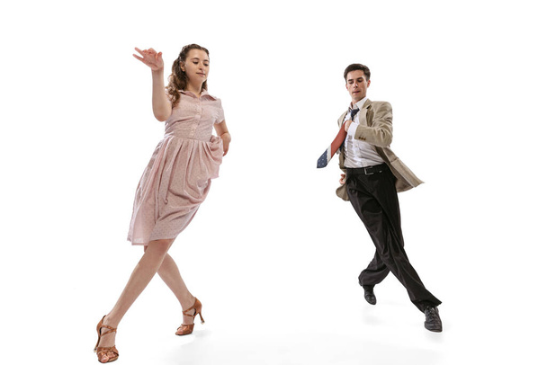 Young man and woman in vintage retro style outfits dancing social dance isolated on white background. Timeless traditions, 1960s american fashion style and art - Foto, imagen