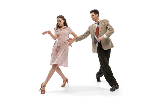 Young man and woman in vintage retro style outfits dancing social dance isolated on white background. Timeless traditions, 1960s american fashion style and art - Foto, imagen