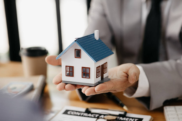 Real estate agents are carrying a housing model of the project to be forwarded to customers as home delivery. Real estate trading ideas and bank loans for buying and selling houses and land. - Foto, Imagem
