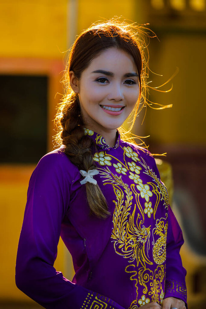 тайська модель у в'єтнамській сукні фіолетовий посміхається фото підсвічування білий баланс помаранчевий ефект
 - Фото, зображення