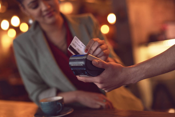 Simplemente deslízalo. Primer plano de una joven mujer robando su tarjeta de crédito para hacer un pago en un café. - Foto, imagen