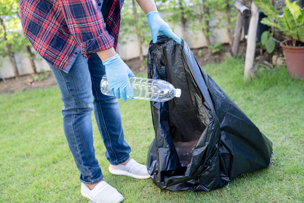 Aziatisch vrouw vrijwilliger dragen water plastic flessen in vuilniszak afval in park, recyclen afval milieu ecologie concept. - Foto, afbeelding