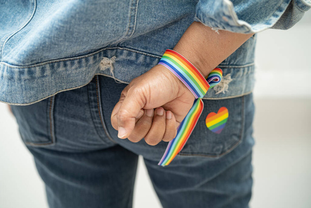 Азиатка в браслетах с радужным флагом, символ месяца гордости ЛГБТ в июне отмечает ежегодный социальный вечер геев, лесбиянок, бисексуалов, транссексуалов, прав человека. - Фото, изображение