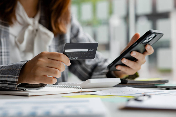 Schöne Frau im Besitz einer Kreditkarte, verwendet sie eine Kreditkarte, um Waren und Dienstleistungen online zu bezahlen, das Konzept der Verwendung einer Kreditkarte für Online-Shopping, die Bestellung von Waren und Dienstleistungen auf der Website. - Foto, Bild