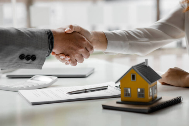 The salesperson of the housing estate in the project and the customer shake hands after successfully signing the contract. Concept of selling housing estates and real estate. - Photo, Image