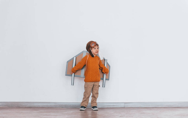 Little boy in retro pilot uniform running with toy plane indoors. - Zdjęcie, obraz