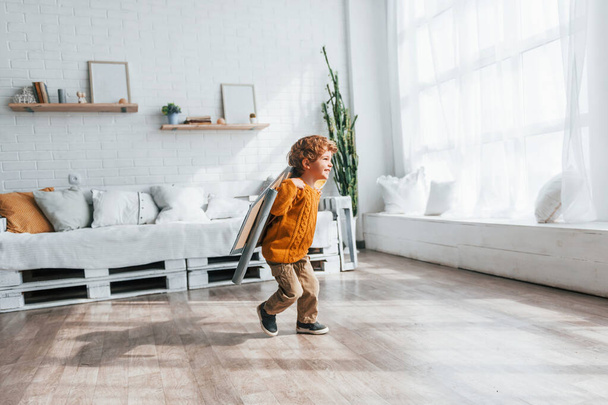 Little boy in retro pilot uniform running with toy plane indoors. - Photo, Image