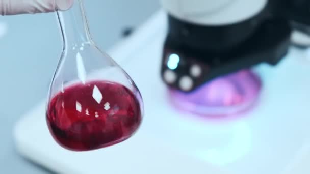 Tiedemies, joka sekoittaa vaaleanpunaista nestettä lasipulloihin - Materiaali, video