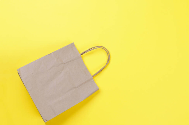 Brown recycled paper shopping bag  on yellow background, ecofriendly concept - Foto, immagini