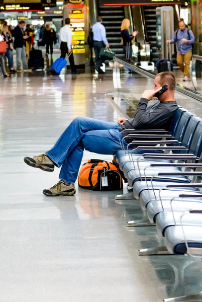 Homme assis parlant au téléphone à un aéroport
 - Photo, image
