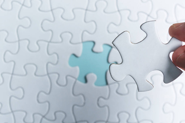 Hand holding piece of jigsaw puzzle. Flat lay, Directly above. Copy space. - Photo, Image