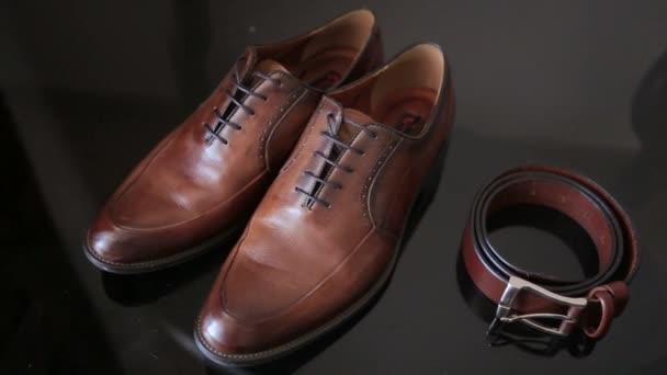 Selective focus of mens leather belt and shoe on table, brown shoes and strap - Video, Çekim