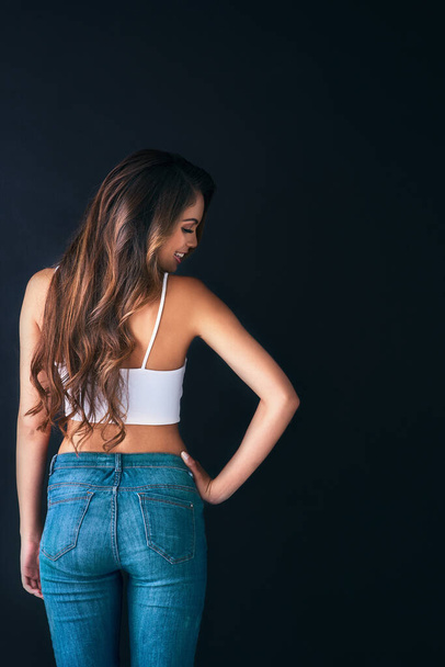 Showing off her silky, sleek curls. Studio shot of an attractive young woman posing against a dark background. - Φωτογραφία, εικόνα