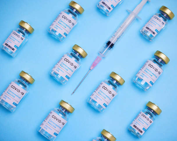 Dit is levensveranderend. Een injectie met vaccins en een spuit tegen een blauwe achtergrond. - Foto, afbeelding