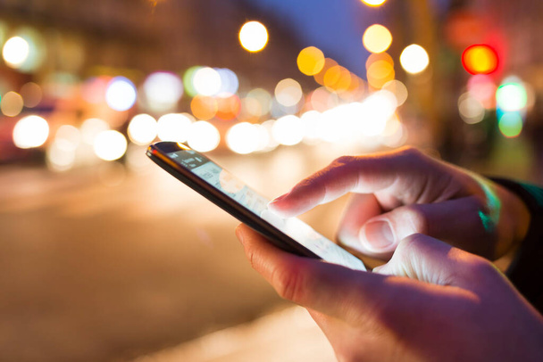 Man using his Mobile Phone in the street, night light bokeh Background - Photo, Image