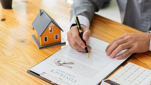 Businessmen holding pens, signing home titles with insurance, care about real estate services and the idea of real estate agents offering interest in installments to their customers. - Foto, imagen