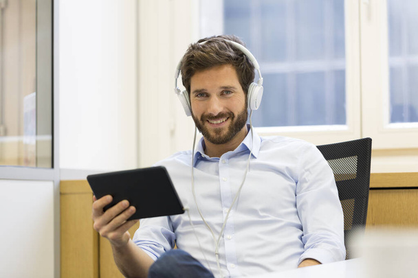 Man in office withe tablet pc and headphones - Photo, image