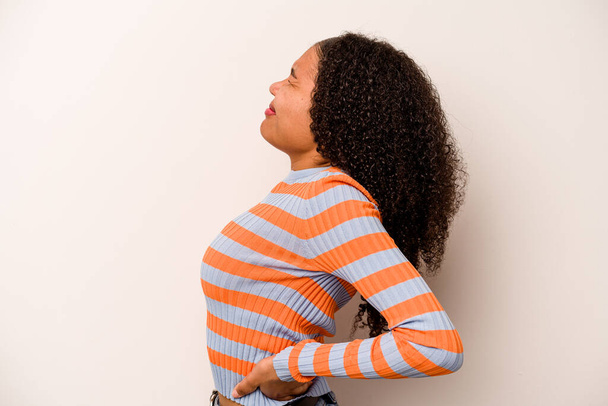 Νεαρή Αφροαμερικανή, απομονωμένη σε λευκό φόντο, που υποφέρει από πόνο στην πλάτη.. - Φωτογραφία, εικόνα