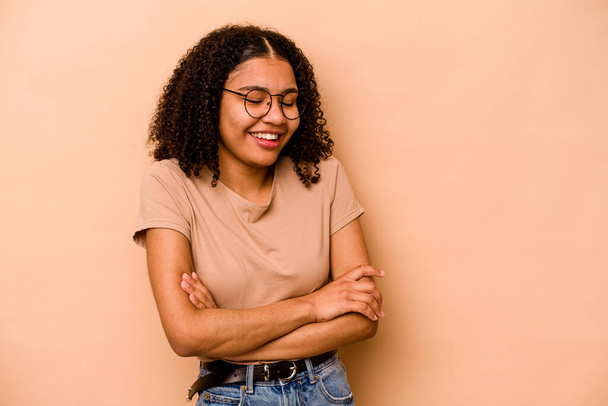Young African American woman isolated on beige background laughing and having fun. - Valokuva, kuva