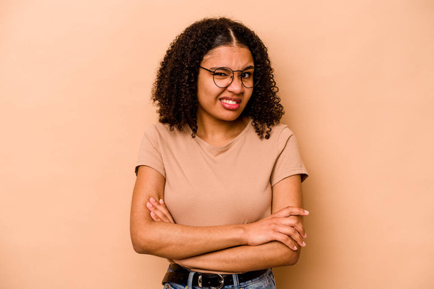 Young African American woman isolated on beige background unhappy looking in camera with sarcastic expression. - Foto, imagen
