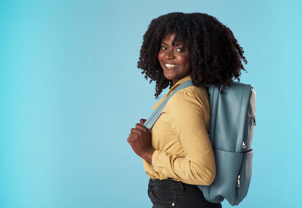 Off to secure my future, be back soon. Studio shot of an attractive young woman carrying a backpack against a blue background. - Photo, Image