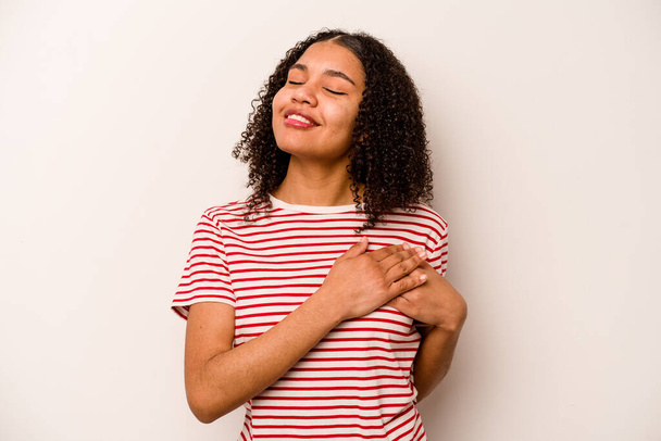 Junge afrikanisch-amerikanische Frau isoliert auf weißem Hintergrund hat einen freundlichen Gesichtsausdruck und drückt die Handfläche auf die Brust. Liebeskonzept. - Foto, Bild