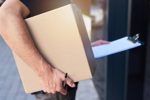 Getting deliveries done on schedule. Cropped shot of a courier holding a box for delivery. - Foto, imagen