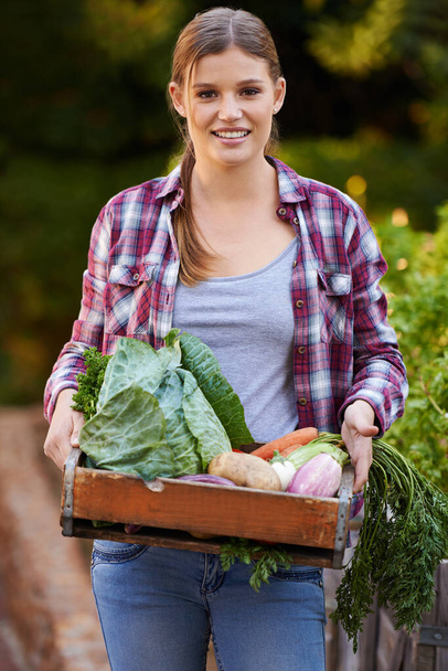 Только органические. Портрет счастливой молодой женщины с ящиком свежих овощей. - Фото, изображение