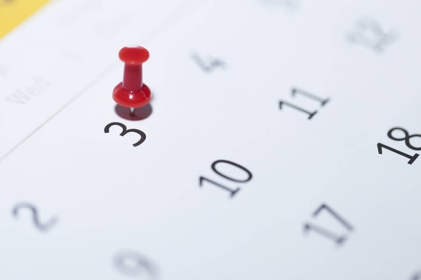close-up van een kalender met een pin op een witte achtergrond - Foto, afbeelding