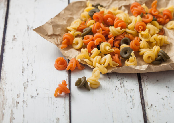 Raw homemade tricolore trottole pasta in brown paper on white. - Foto, afbeelding