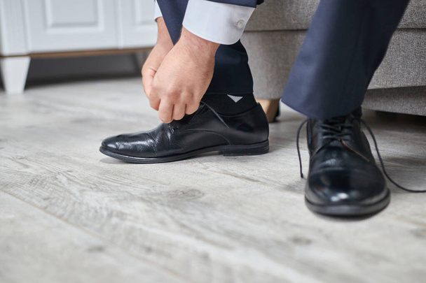 καλλιεργημένη άποψη του ανθρώπου βάζοντας τα παπούτσια στο πάτωμα - Φωτογραφία, εικόνα