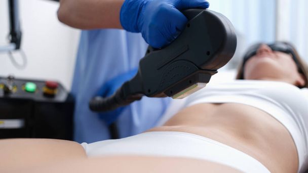 Kosmetologe entfernt unerwünschte Haare aus dem Körper des Klienten mittels Laser-Nahaufnahme - Foto, Bild
