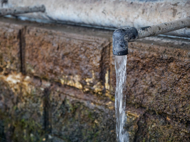 Sauberes Trinkwasser fließt kontinuierlich aus dem Wasserhahn einer natürlichen Quelle. Es fehlt an sauberem Trinkwasser. Dürre. - Foto, Bild