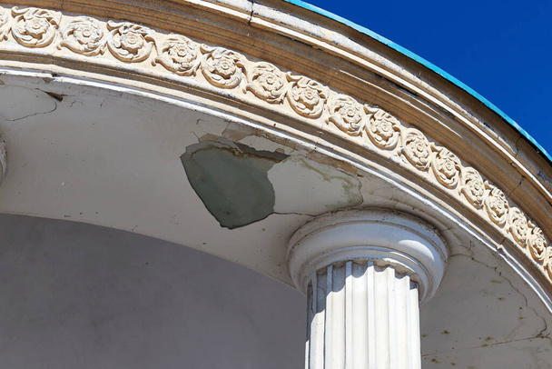 fragment of old rotunda with a column and decorative stucco, and with fallen plaster - Photo, image