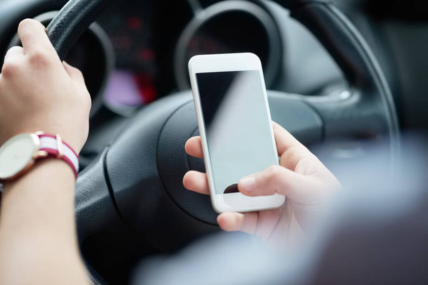 Keep your eyes on the road and avoid distracted driving. Closeup shot of an unrecognizable man using his cellphone while driving. - Photo, Image