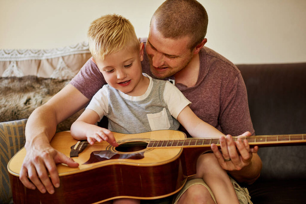 Hora de otra lección de guitarra con papá. Recortado disparo de un padre y su pequeño hijo tocando la guitarra juntos en casa. - Foto, imagen
