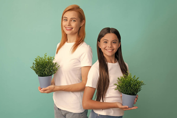 Rodzina adopcyjna adoptowanego dziecka córka i kobieta matka uśmiechają się trzymając rośliny doniczkowe, przybrane - Zdjęcie, obraz