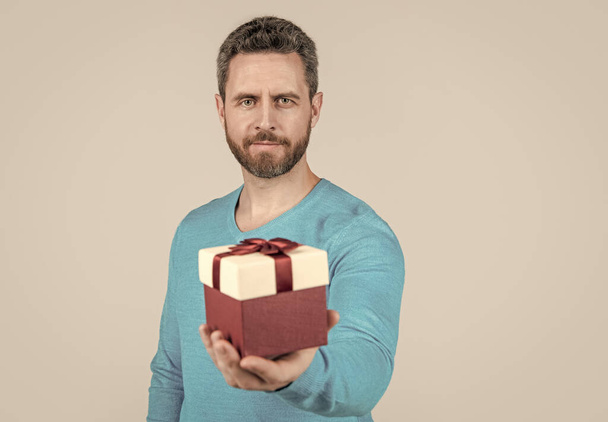 for you. giftbox in hand of successful handsome man. selective focus. bearded man with business reward - Photo, Image