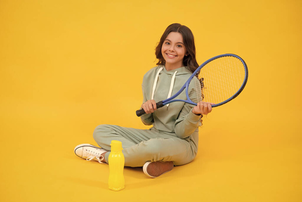 niño sentarse con raqueta y botella de agua. niño con raqueta de tenis. adolescente chica después de deporte entrenamiento. - Foto, imagen