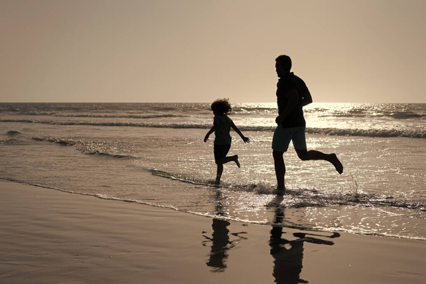 otec a syn siluety běh baví a cítit svobodu na letní pláži, letní dovolená - Fotografie, Obrázek